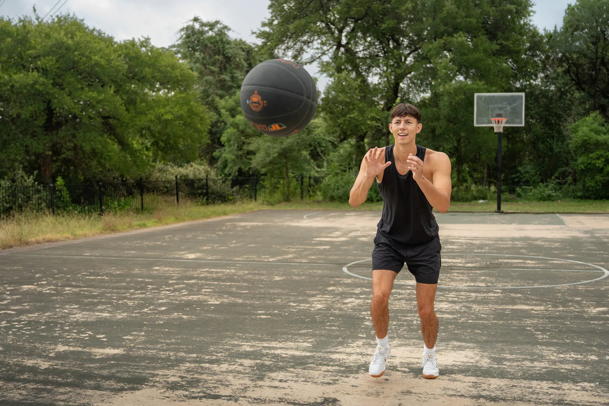 Player catching a Spalding TF DNA basketball on an outdoor court